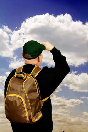 male tourist with a backpack and a baseball cap looks up at the sky with clouds.
の写真素材