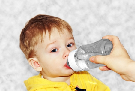 small child drinks water from a bottle with a nipple.の写真素材