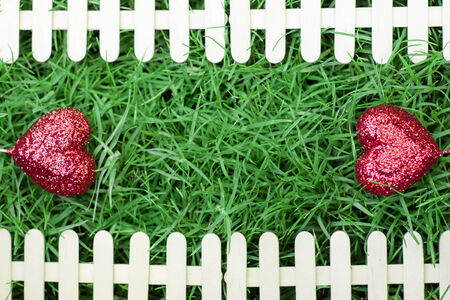 Red hearts on green grass background and fence for Valentines Dayの写真素材