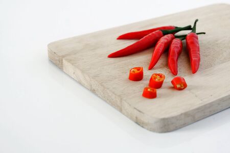 Red Chilis on chopping board, white background.の写真素材
