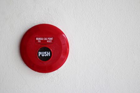 Red fire alarm mounted on cement wall for warning and security system.の写真素材