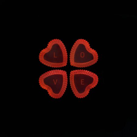 Heart shape red jellies contain letter LOVE on black background.の写真素材
