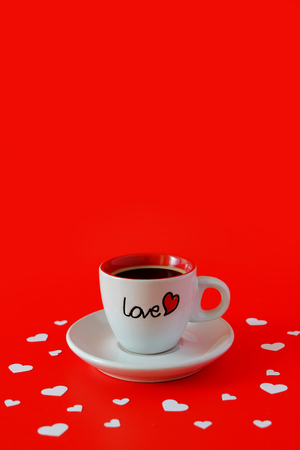 White coffee cup surrounded by white paper heart on red background. Copy space on top.の写真素材