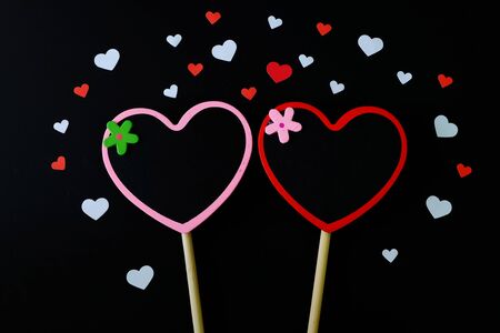 Couple of small heart shape blackboard surrounded by white and red paper heart on black background.の写真素材