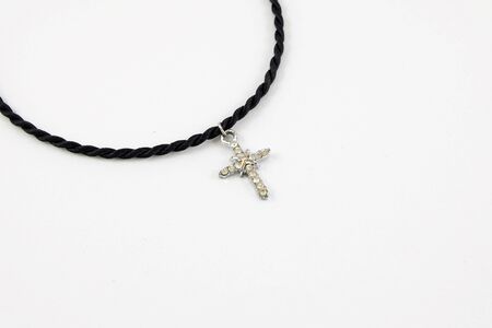 Crucifix hang on wax cord necklace on white background.の写真素材