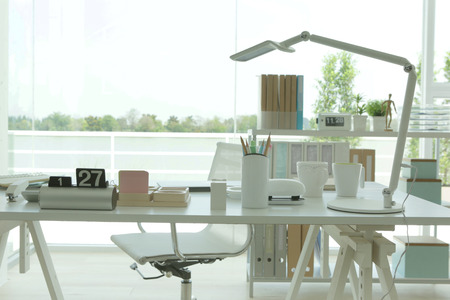 the desktop office with a lot of stuff in a modern white officeの写真素材