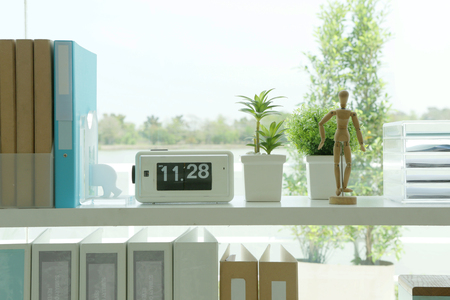 on the book shelf have a clock, a model, plants and lot of foldersの写真素材