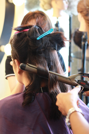 hairstylist doing curly hair for clientの写真素材