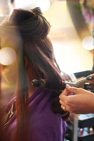 stylist rolling customers hair with curling ironのeditorial素材
