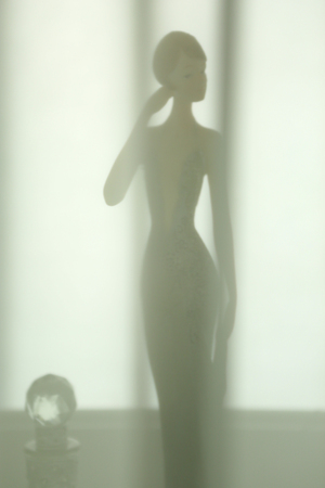 a woman figure doll put behind silk curtain look softly