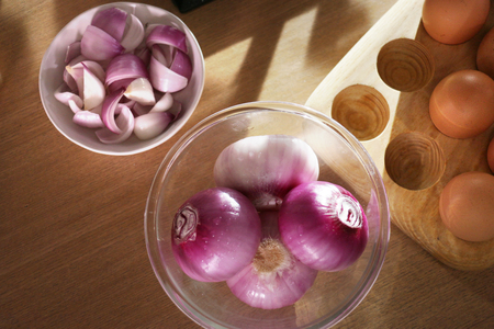 red onions are peeled cleaned and sliced in a cup and a glass bowl in kitchenの写真素材