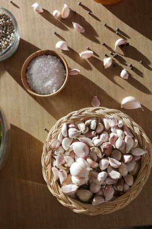 a basket of garlic, a cup of salt and a bowl of pepperの写真素材