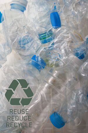 the pile of empty plastic bottles and a reclycle symbol on the white background in verticalの写真素材