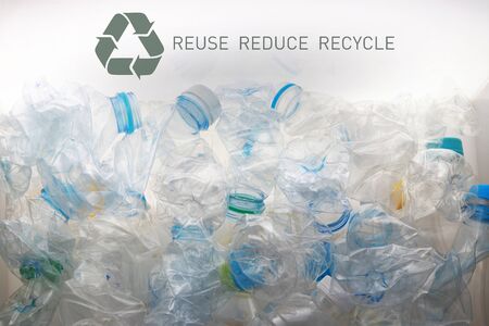 pile of crushed plastic bottles and recycle symbol put in a white backgroundの写真素材