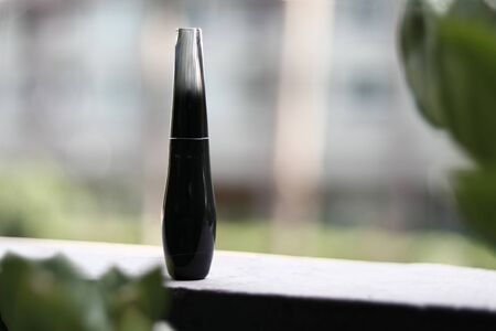 a packaging shot of black glass perfume bottle put in natural backgroundの写真素材