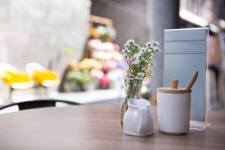 white ceramic milk mug and sugar jar put with menu stand on a table of sidewalk cafeの写真素材