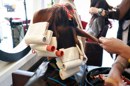 hairdresser straight some hair prepare for rolling with a rod for perming step in salonの写真素材