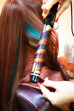 a professtional hairdressing is ironing multicolored hair and look like spiral rainbowの写真素材