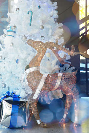 a christmas wreath decorated with a golden hear deer, white snowflakes and red balls put on a stand in hall wayの写真素材