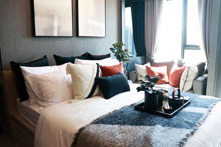 a modern bedroom with a lot of pillows and cushions on the bed and sofaの写真素材