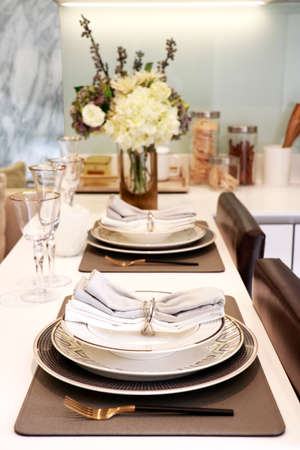 tableware for dinner consis of three size plates with two wine glasses, knife and fork, two napkins put on the counter in kitchenの写真素材