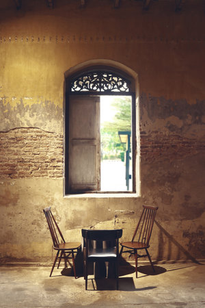 one table and three chairs are putting under the antique window in pop up cafe