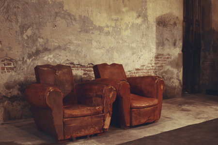 two old sofas put in abandoned building in front of crack wallの写真素材