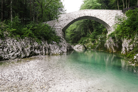Beautiful wild river in the national park. Emerald color river flows through unspoiled nature. Wilderness all around. Ancient stone bridge.の写真素材