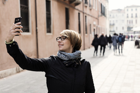 Traveling around the world. Beautiful modern woman making selfie. Local sights in the background.の写真素材