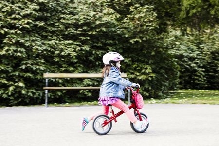 The little girl enjoying a bike ride through the park. Healthy lifestyle, safety first.の写真素材