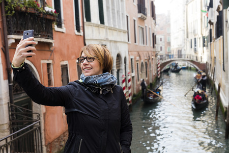 Traveling around the world. European cities. Beautiful modern woman making selfie. Local sights in the background.の写真素材