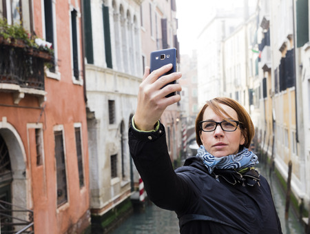 Traveling around the world. European cities. Beautiful modern woman making selfie. Local sights in the background.の写真素材