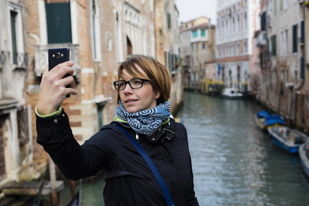 Traveling around the world. European cities. Beautiful modern woman making selfie. Local sights in the background.の写真素材