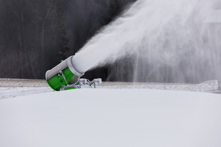 Making snow on the ski track. Artificial snow in the ski resort. Snow machine spews snow.の写真素材
