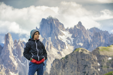 Boy on the trip in to the high mountains. Boy hiking through national park. High mountain peaks in the background.の写真素材