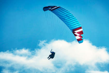 Paraglider flying over the mountains. Active people enjoying in extreme and adrenalin sports....