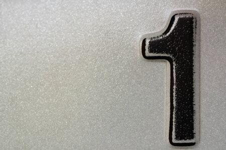 Black number one spray on white reflective metal surface. background, texture
