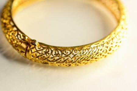 Gold color bracelet isolated on white background. Macro photography.