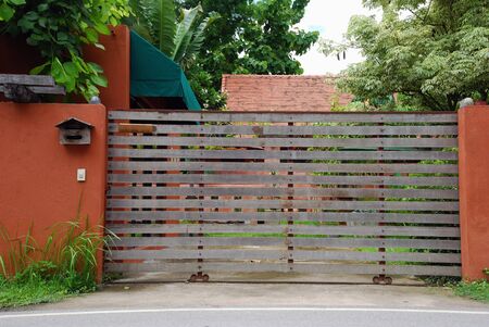 Automatic sliding wooden gate and red brick wall of Bali Style House.