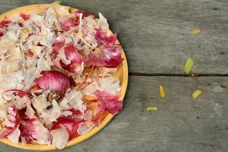 Garlic peel in yellow dish on wooden floor background.の写真素材