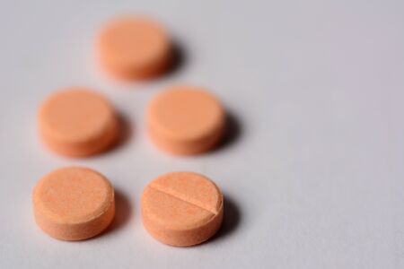 Orange color tablet pills isolated on gray background.の写真素材