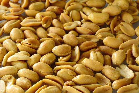 Peeled and salt roasted peanuts, abstract background.