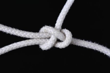 A white rope tied with sheet bend knot isolated on black background.の写真素材