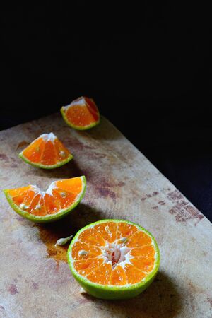 Fresh orange fruit slice on wooden cutting board isolated on dark background.の写真素材