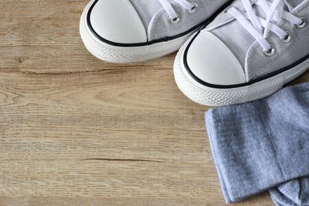 White color canvas shoes and gray socks isolated on wooden background.
