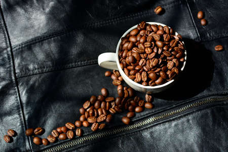 Coffee beans and white mug isolated on black leather background.の写真素材