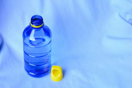 A blue plastic bottle water with yellow bottle cap isolated on blue sky background.の写真素材