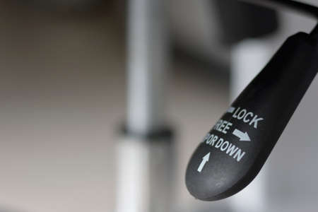 Closeup of black lever adjustable for lifting office chair mechanism.