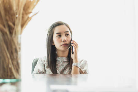 Pretty young woman working on a table with natural white background.の写真素材