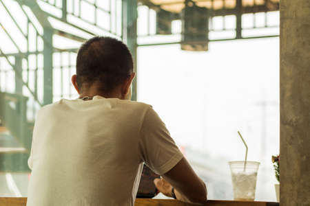 Young man in white T-shirt sit back in coffee shop.